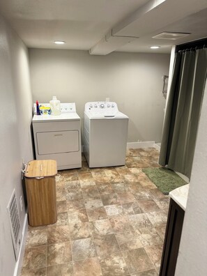 Laundry room with washer, dryer, and trash bin.