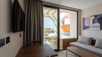 Una habitación moderna con una mesa de comedor, un sofá, un televisor y un ventanal corredera a un área exterior.