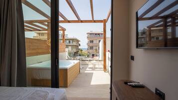 Un dormitorio con cama, un banco de madera, un televisor y vistas al patio exterior.