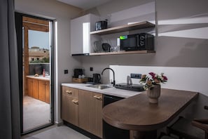 A modern kitchen with wooden cabinets, a built-in microwave, and a small dining area with a wooden table and chairs.