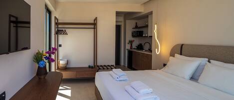 Ein modernes Hotelzimmer mit einem großen Bett, einer hölzernen Bank, einem Schreibtisch und einem Spiegel.