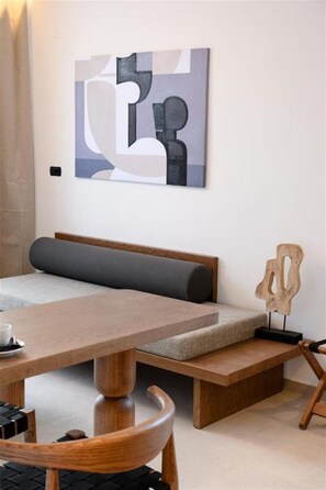 A modern room with a wooden dining table, a bench with cushions, and a wall-mounted abstract art piece.