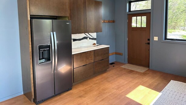 Una cocina moderna con un refrigerador de acero inoxidable, armarios de madera y una ventana que ofrece luz natural.