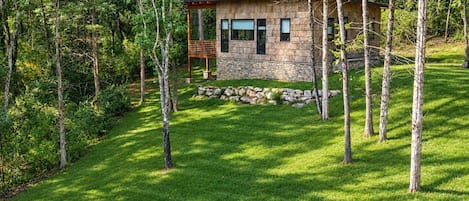 A small stone cabin surrounded by a well-maintained lawn and trees.