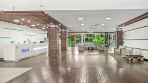 A reception area with a 'tours' desk, wooden flooring, and a seating area with a view of greenery. - Belle Escapes  - Drift Beachfront Resort Suite 3402 (Palm Cove)