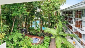 A lush indoor garden with a pool, surrounded by tall trees and various plants. - Belle Escapes  - Drift Beachfront Resort Suite 3402 (Palm Cove)
