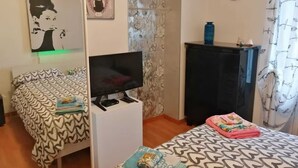 Un dormitorio con cama, televisor, escritorio y armario.
