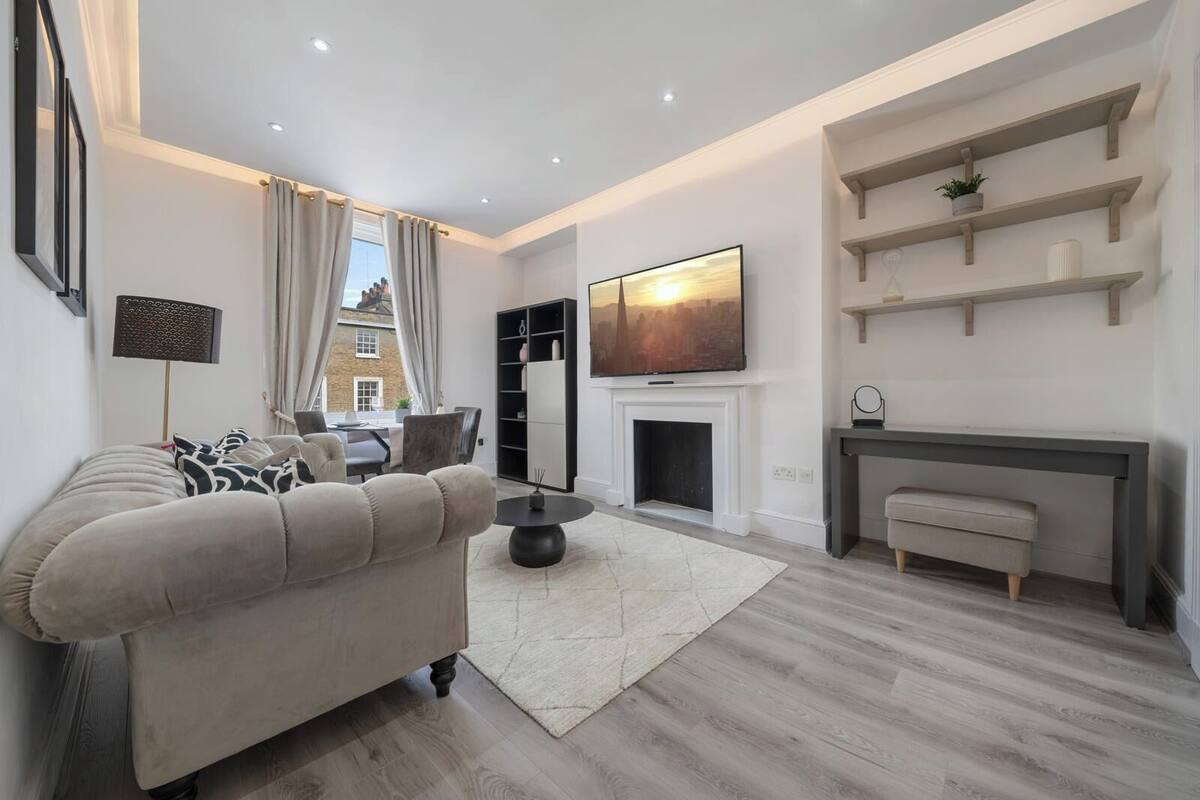 A modern living room with a sofa, a fireplace, a TV, and built-in shelves.