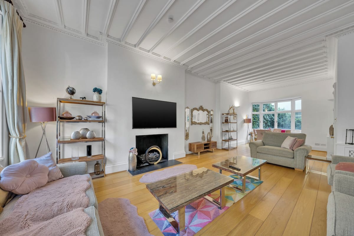 A spacious living room with a fireplace, a large flat-screen TV, and a comfortable seating area with sofas and a coffee table.