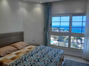 A bedroom with a bed, a view of the sea, and a window with curtains. - Juliana Beach Hurghada (Hurghada)