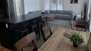 A modern kitchen with a central island, dining chairs, a wooden table, and a potted plant. - Entire chalet with Spa near Lake & Beach (Entrelacs)