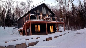 A two-story log cabin with a balcony, surrounded by snow and trees. - Entire chalet with Spa near Lake & Beach (Entrelacs)