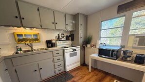 A compact kitchen with white cabinets, a stove, a microwave, and a sink. - Artful Asheville Oasis ~ Private Hot Tub, Fire Pit, Peaceful Wooded Stay (Swannanoa)