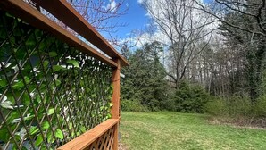 A wooden fence with a lattice design, a grassy lawn, and trees in the background. - Artful Asheville Oasis ~ Private Hot Tub, Fire Pit, Peaceful Wooded Stay (Swannanoa)