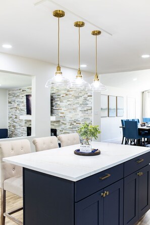 A modern kitchen with a marble island, dark cabinetry, and three pendant lights. - 1 Mi. to Notre Dame, Irish Pub, Hot Tub, 4800sq ft (South Bend)