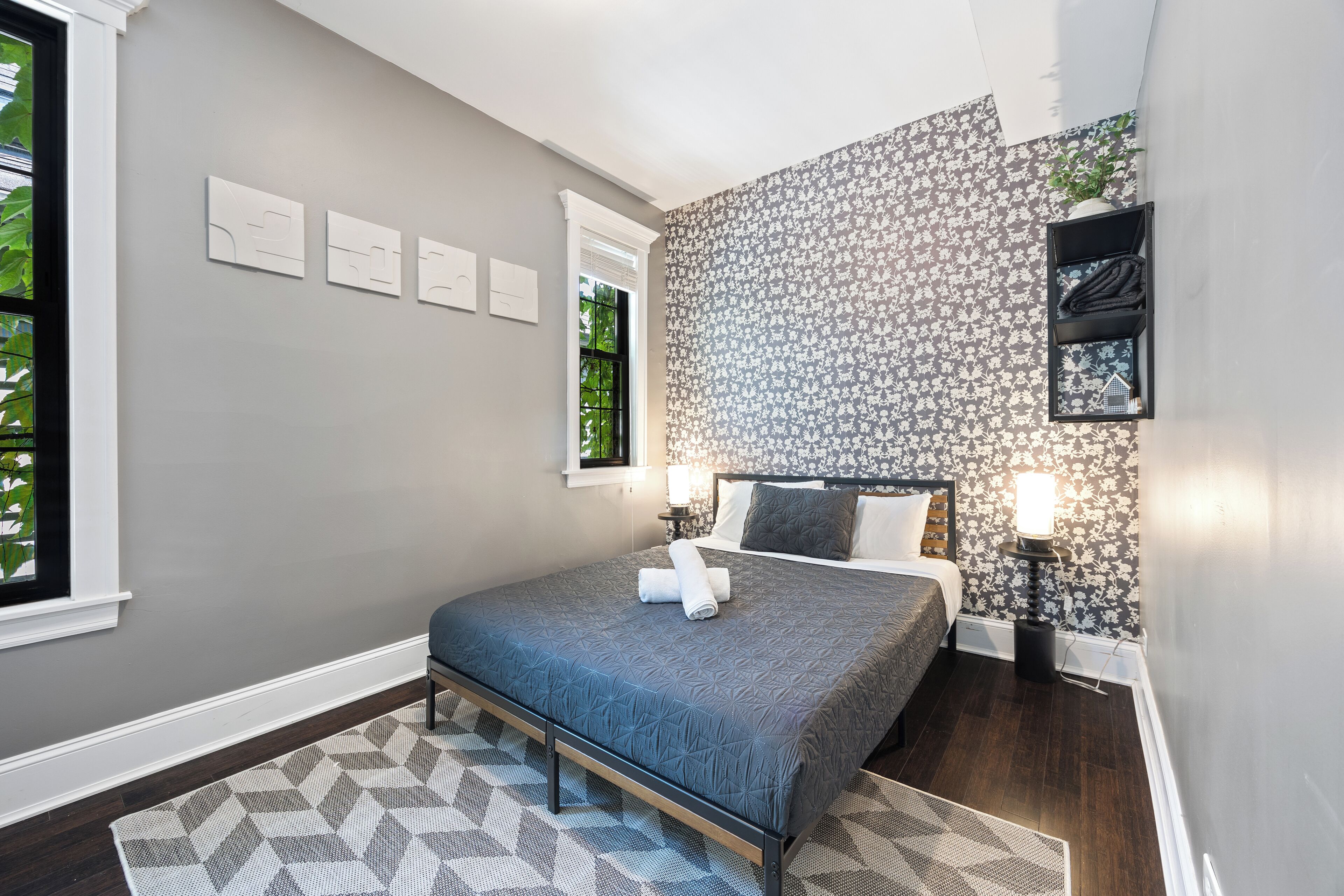 Ein Schlafzimmer mit einem Bett, einer Wand mit Muster und einem Fenster.