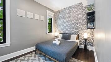Ein Schlafzimmer mit einem Bett, einer Wand mit Muster und einem Fenster.