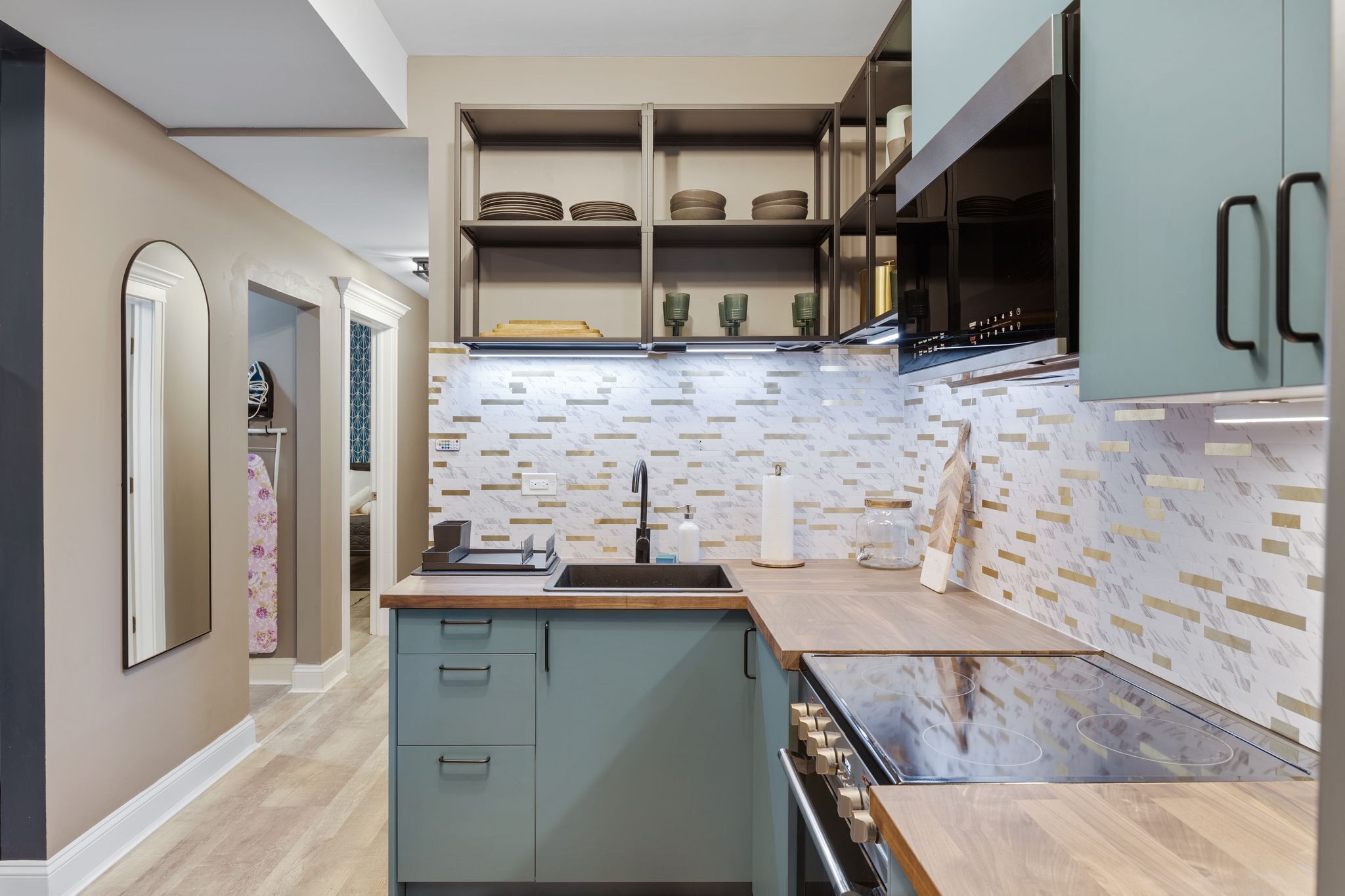 A modern kitchen with a central island, built-in shelves, and a patterned backsplash.