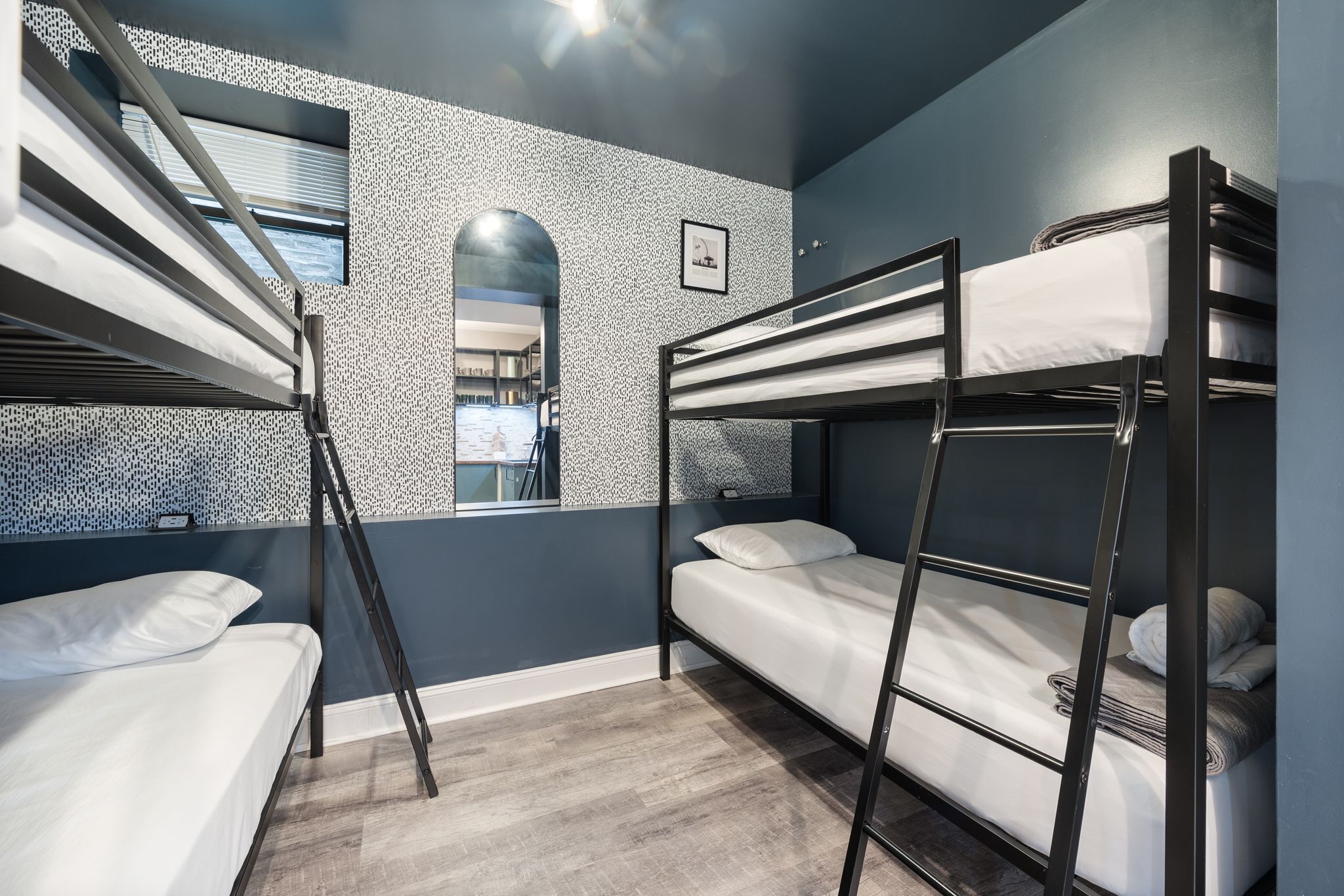 A bunk bed room with a window, a ladder, and a small framed picture on the wall.
