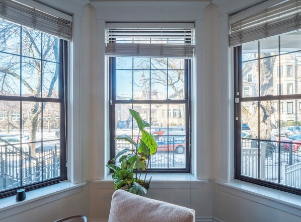 A room with large windows, a potted plant, and a white towel on a bench. - Wrigleyville Suites (Chicago)