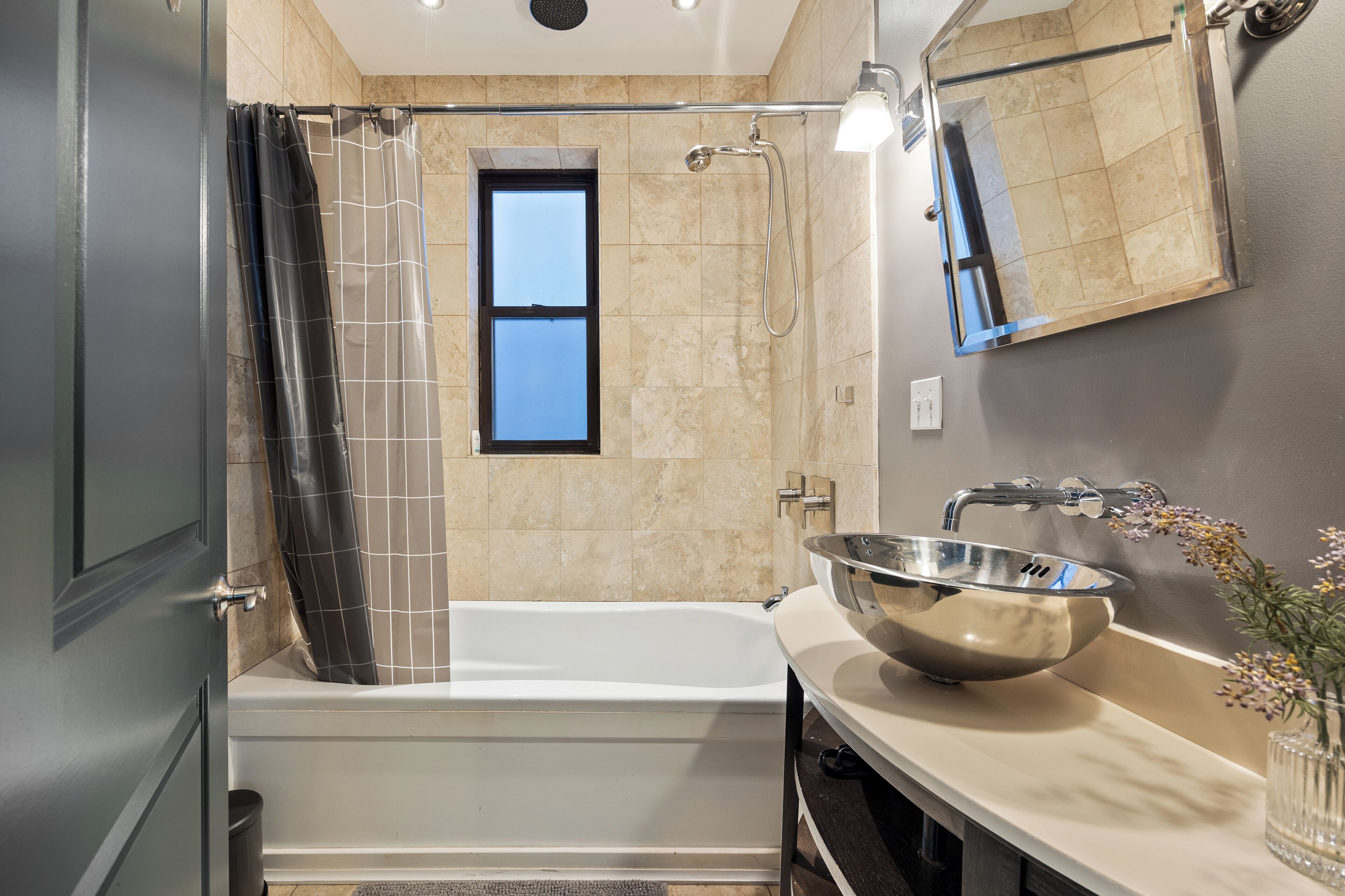A modern bathroom with a bathtub, shower, and a large mirror.