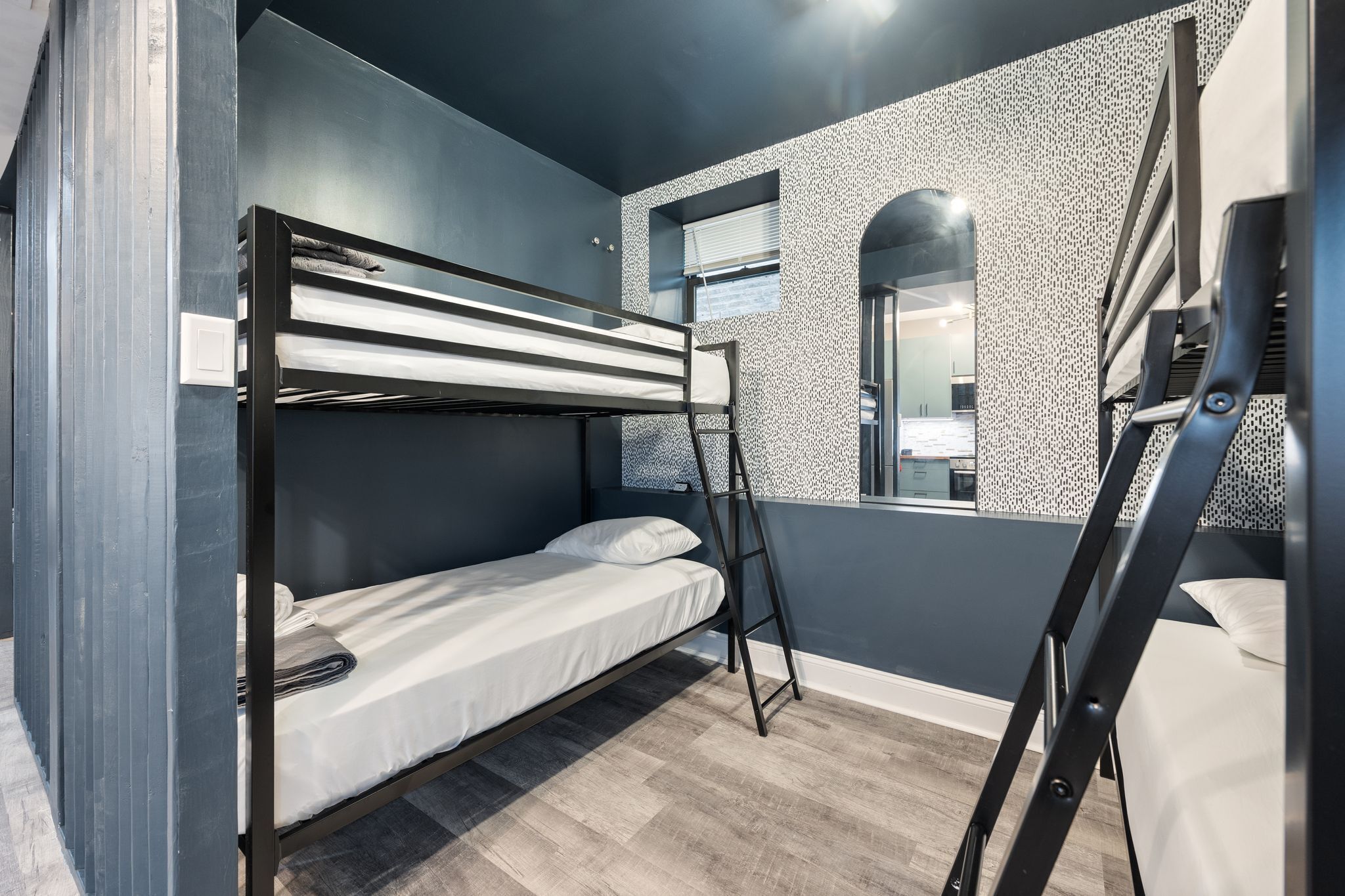 Camera con letto a castello, una scala, una finestra con persiane e una parete decorata.