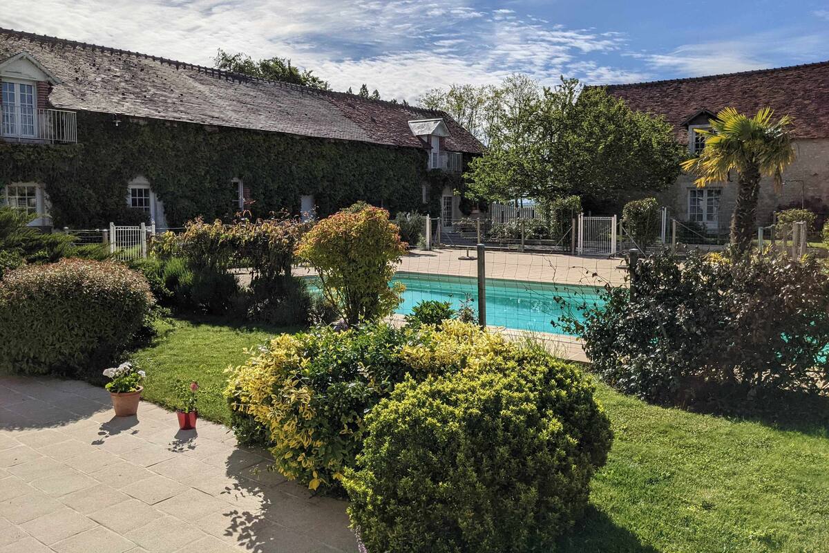 Un pati amb piscina, envoltat de tarrons ben cuidats i un edifici amb teulada enrajolada.