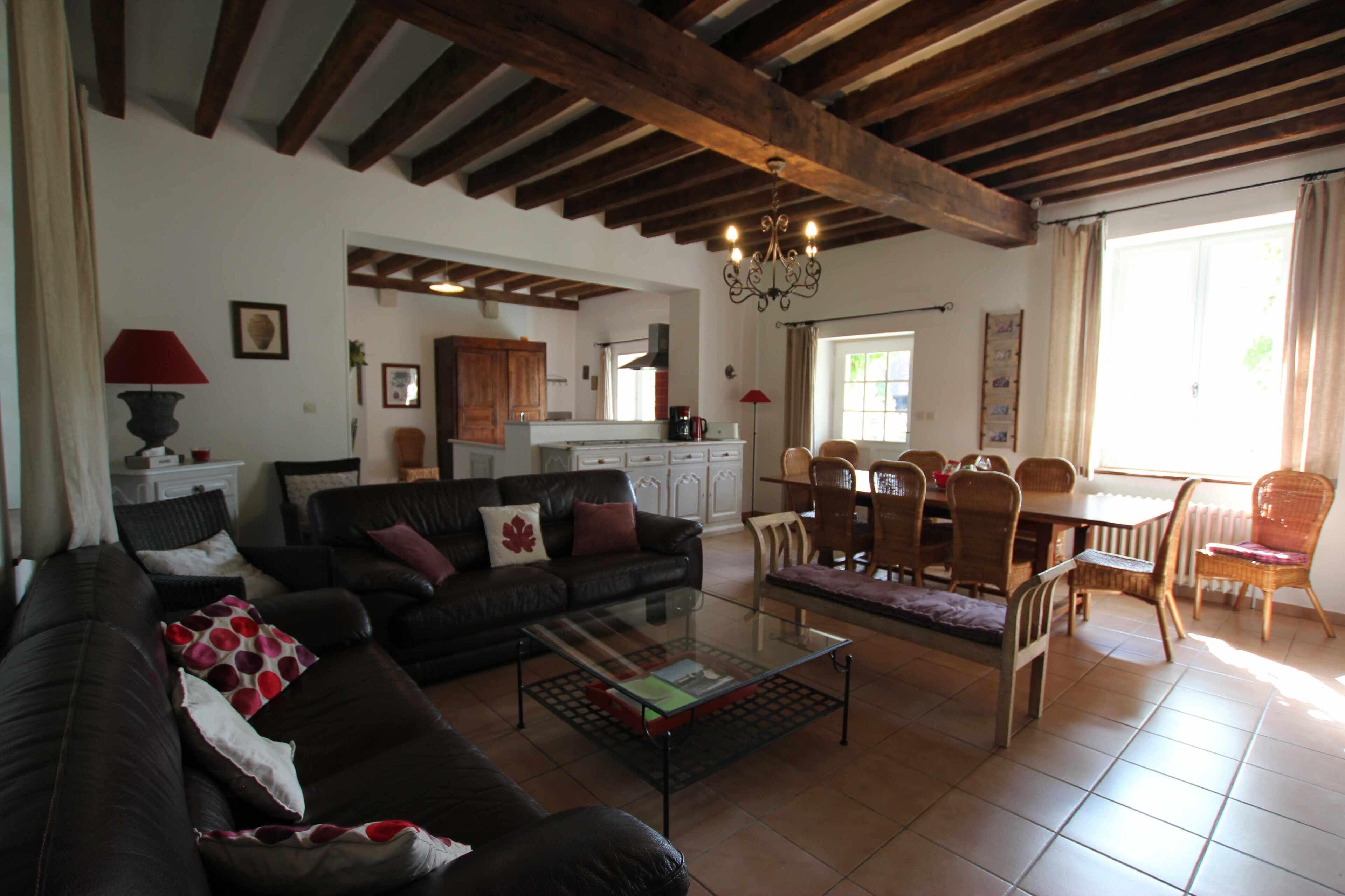 A living room with a sofa, coffee table, and dining area with chairs and a table.