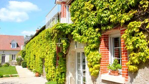 A house with ivy-covered walls, a brick facade, and a white door. - Domaine de Champouteau (Averdon)