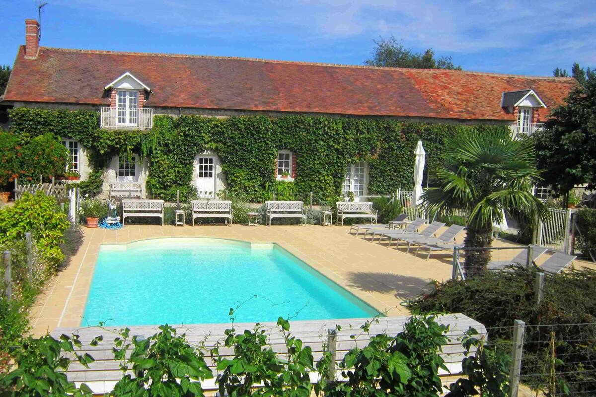 Una casa espaiosa amb piscina, envoltada de vegetació exuberant i un jardí ben cuidat.