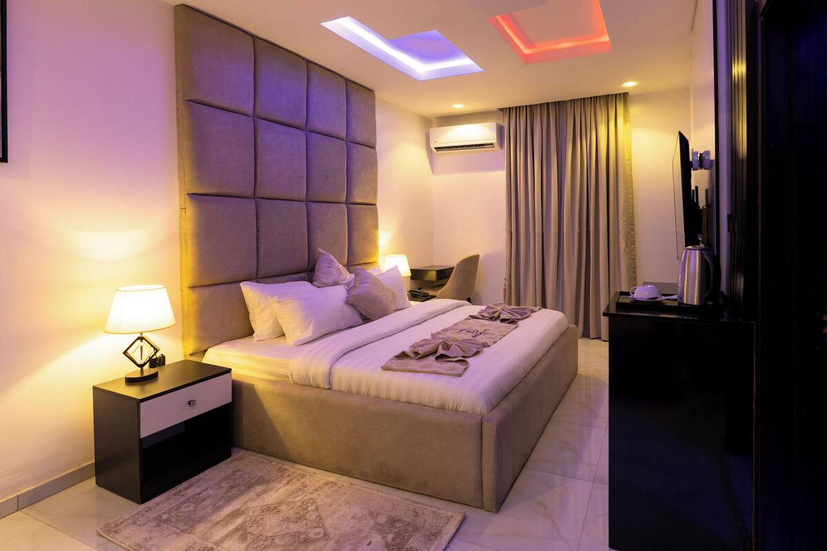 A modern hotel room with a large bed, bedside tables, a desk, and a TV.