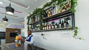 Zona de bar con un cantinero, estanterías llenas de botellas de vino y copas de vino colgantes.