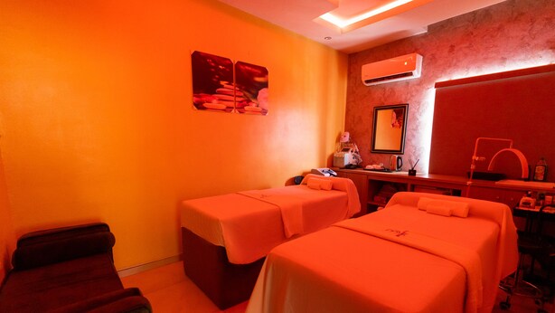 A room with two beds, a desk, a chair, a mirror, and a massage table. - BRIMUYO HOTEL (Lagos)