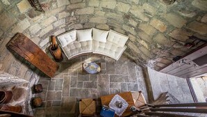 A stone-walled room with a curved bench, wooden furniture, and a rustic atmosphere.