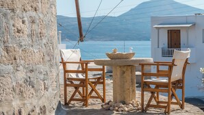 A stone table with a bowl, two wooden chairs, and a stone wall.