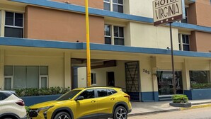 A yellow SUV parked in front of a building with a sign reading "HOTEL VIRGINIA." - Hotel Virginia (Oaxaca)