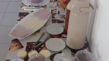 Una mesa de bufé con diversos alimentos y recipientes, incluyendo una jarra grande y varios platos cubiertos.