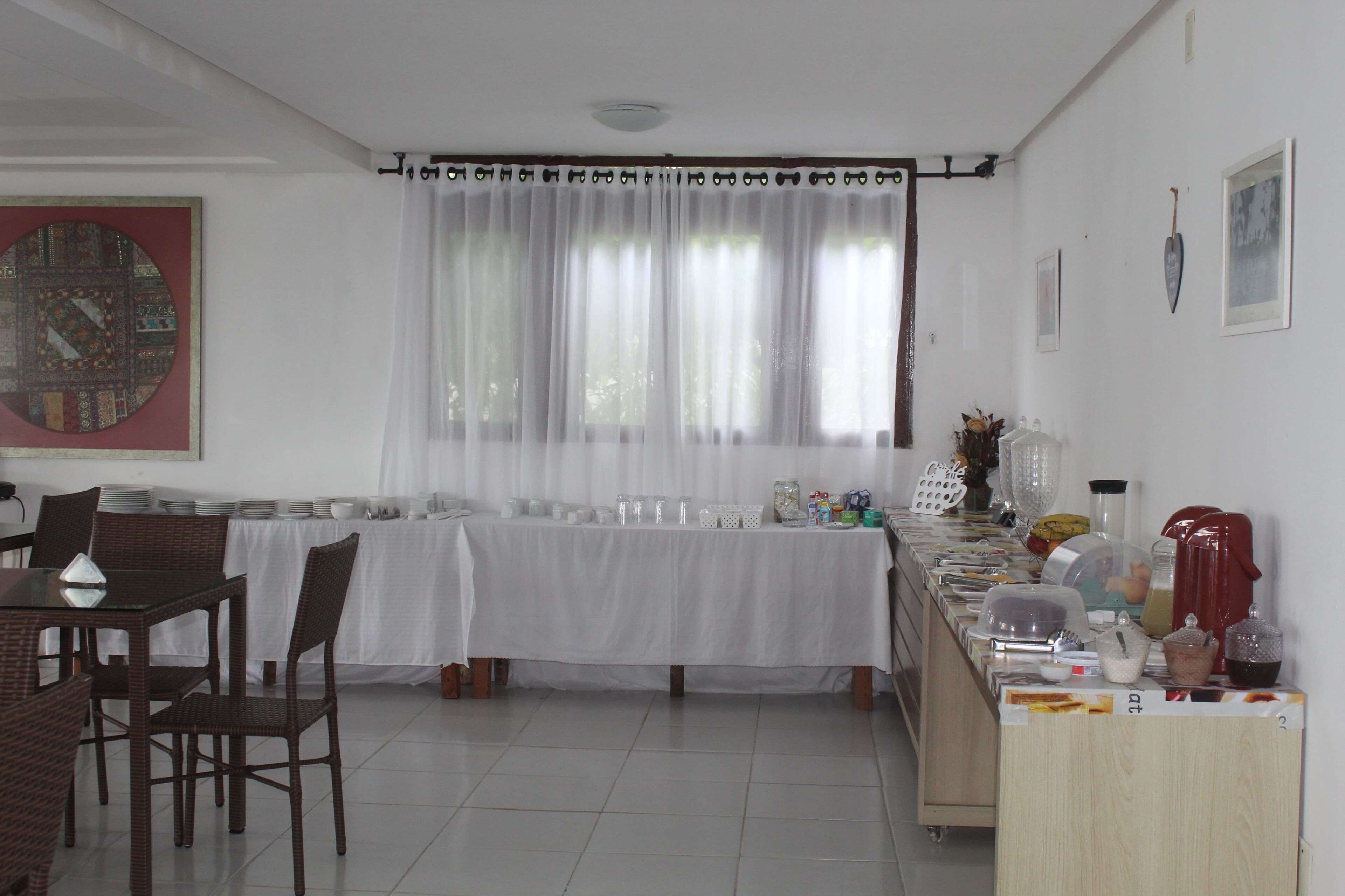 Un comedor con una mesa dispuesta para cuatro, una barra de buffet con diversos alimentos y un reloj decorativo grande en la pared.
