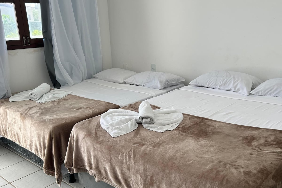 Una habitación de hotel con dos camas, cada una con una manta marrón y almohadas blancas.