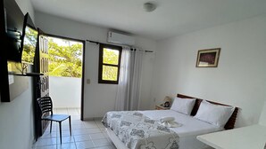 Un dormitorio con cama, una silla, un escritorio, una ventana y un cuadro en la pared.