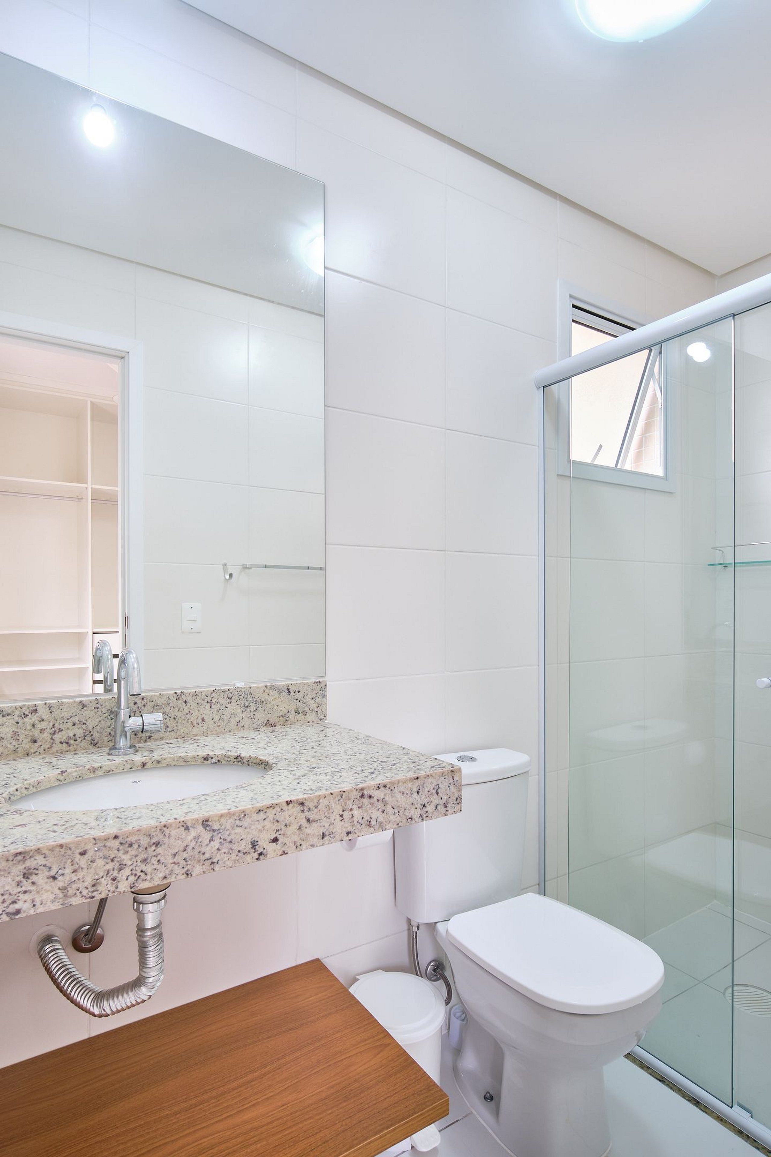 Et moderne badeværelse med bordplade i granit, et hvidt toilet og en brusekabine i glas.