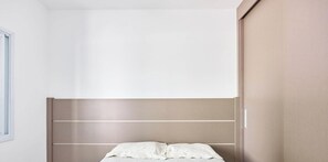 Un dormitorio con cama, armario y ventana.