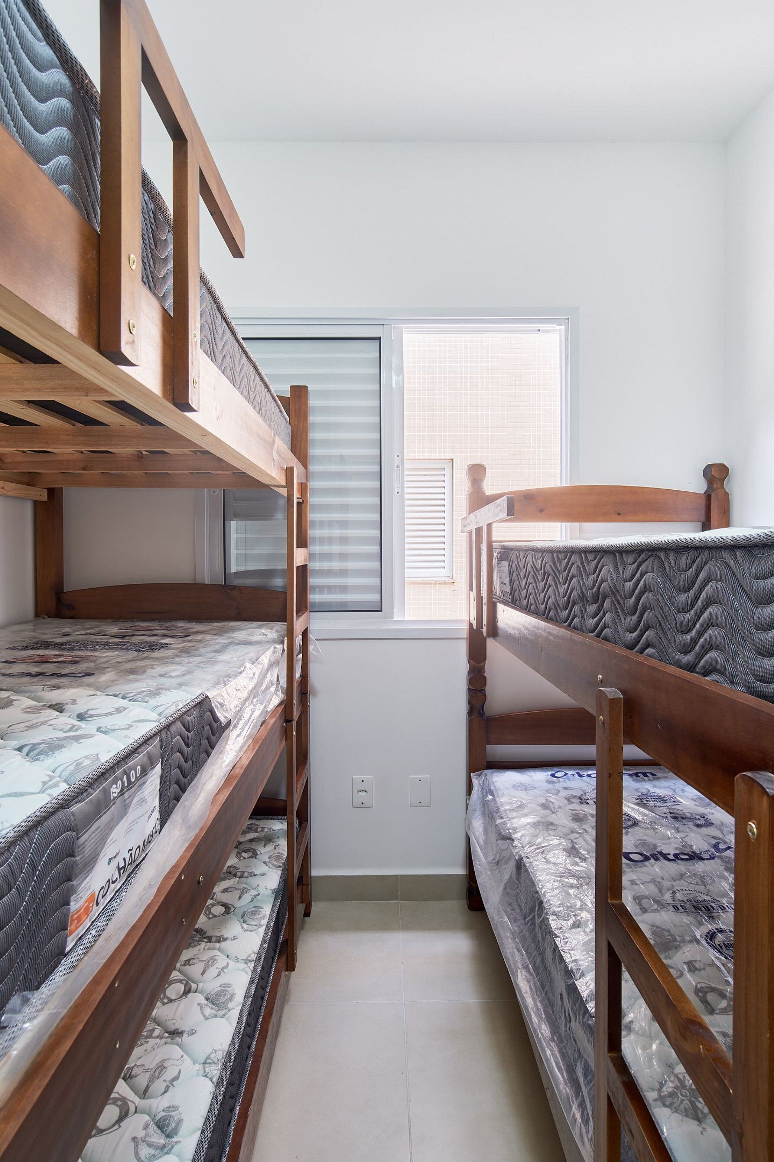 Una habitación con dos literas, una ventana con persianas y piso de baldosas.