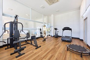 Un gimnasio con equipo de ejercicio, cinta de correr y trampolín.