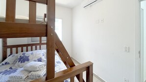 A bedroom with a bunk bed, an air conditioning unit, and a ceiling fan. - Residencial Saint Barth (Ubatuba)