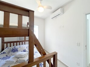 A bedroom with a bunk bed, an air conditioning unit, and a ceiling fan. - Residencial Saint Barth (Ubatuba)