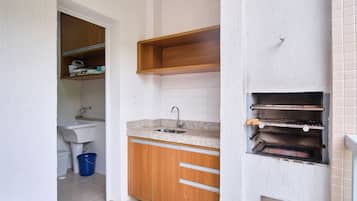 Een kleine keuken met een spoelbak, houten keukenkastjes en een inbouwoven.