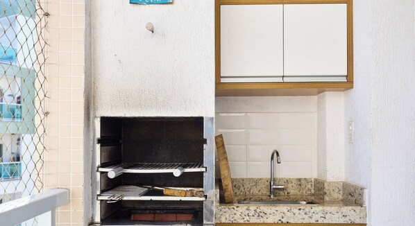 Una cocina con una parrilla empotrada, un fregadero y un armario sobre la encimera.