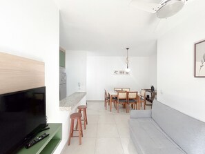 A compact living space with a TV, seating area, and dining setup. - Residencial Saint Barth (Ubatuba)