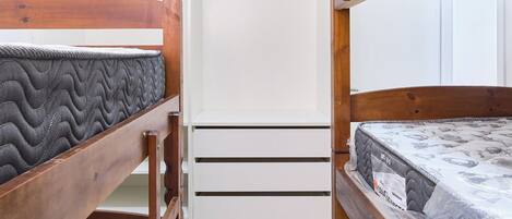 Ein Zimmer mit Etagenbetten, einem weißen Kleiderschrank und Fliesenboden.